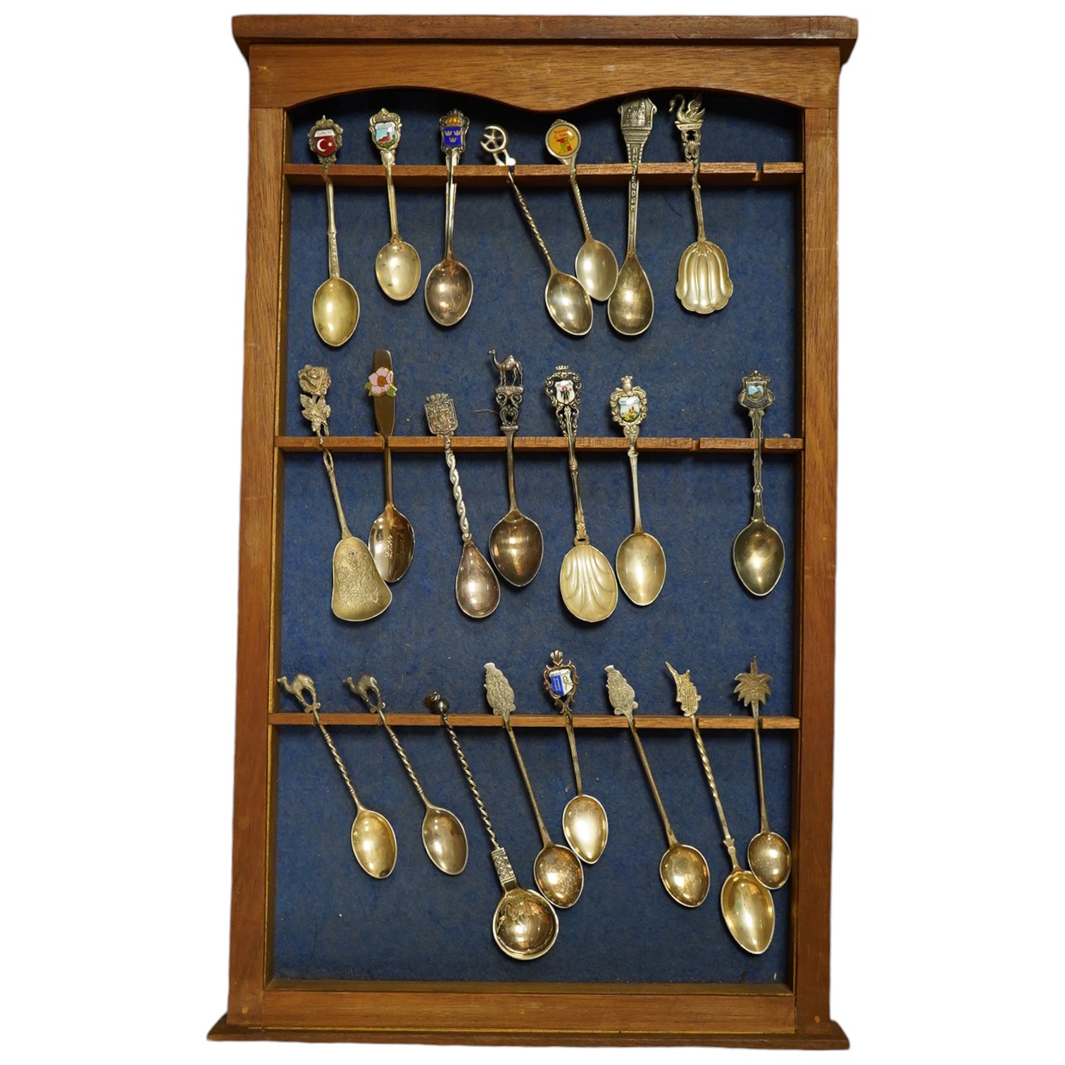 A quantity of collectors spoons from various countries, some silver with enamel, housed in a cabinet. Condition - fair